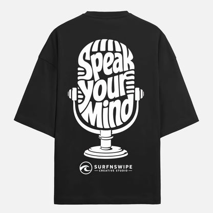Black t-shirt with white microphone graphic and text 'Speak Your Mind' on a light gray background