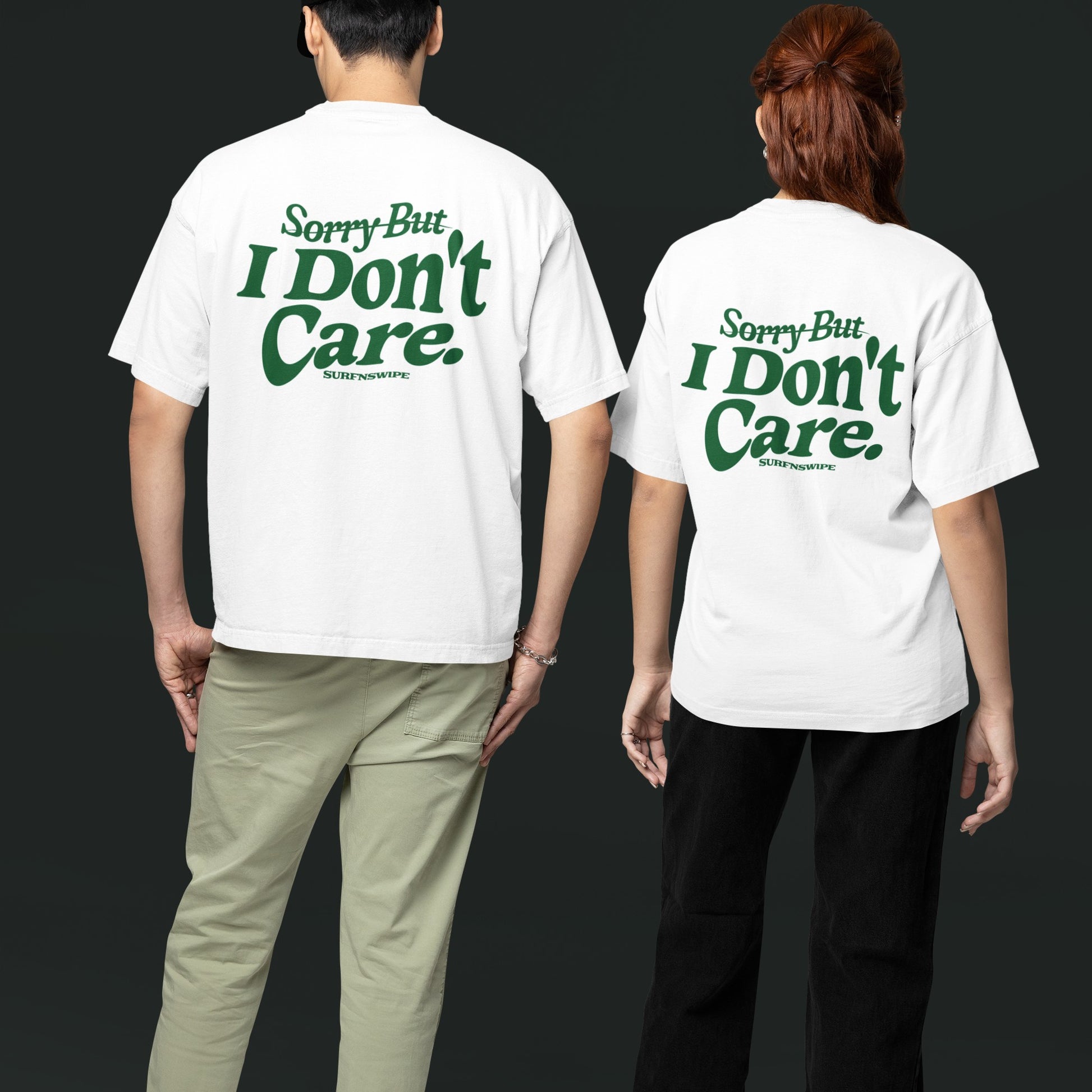 A man and a woman wearing white oversized tees with green text graphic on the front.