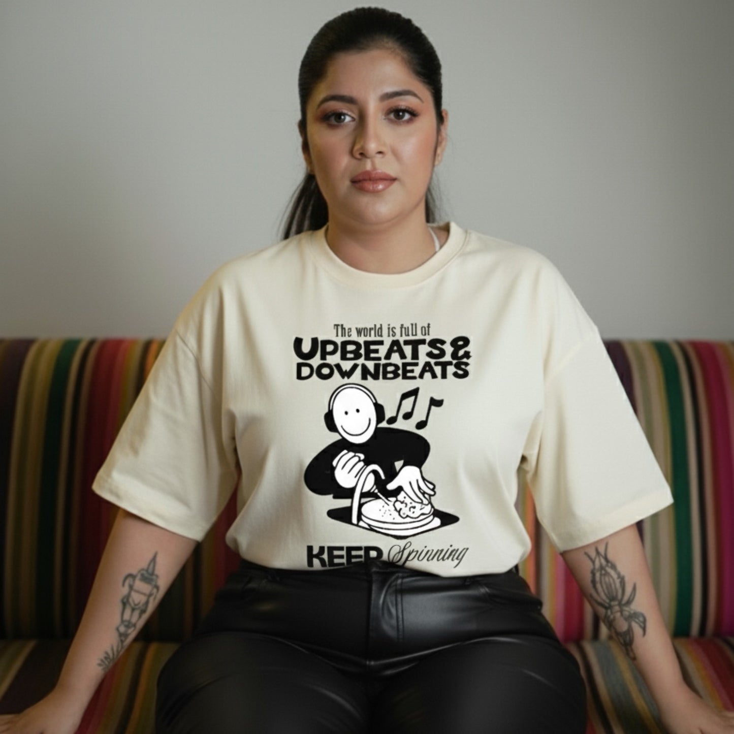 Woman wearing a t-shirt with a graphic design and text, sitting on a colorful couch.
