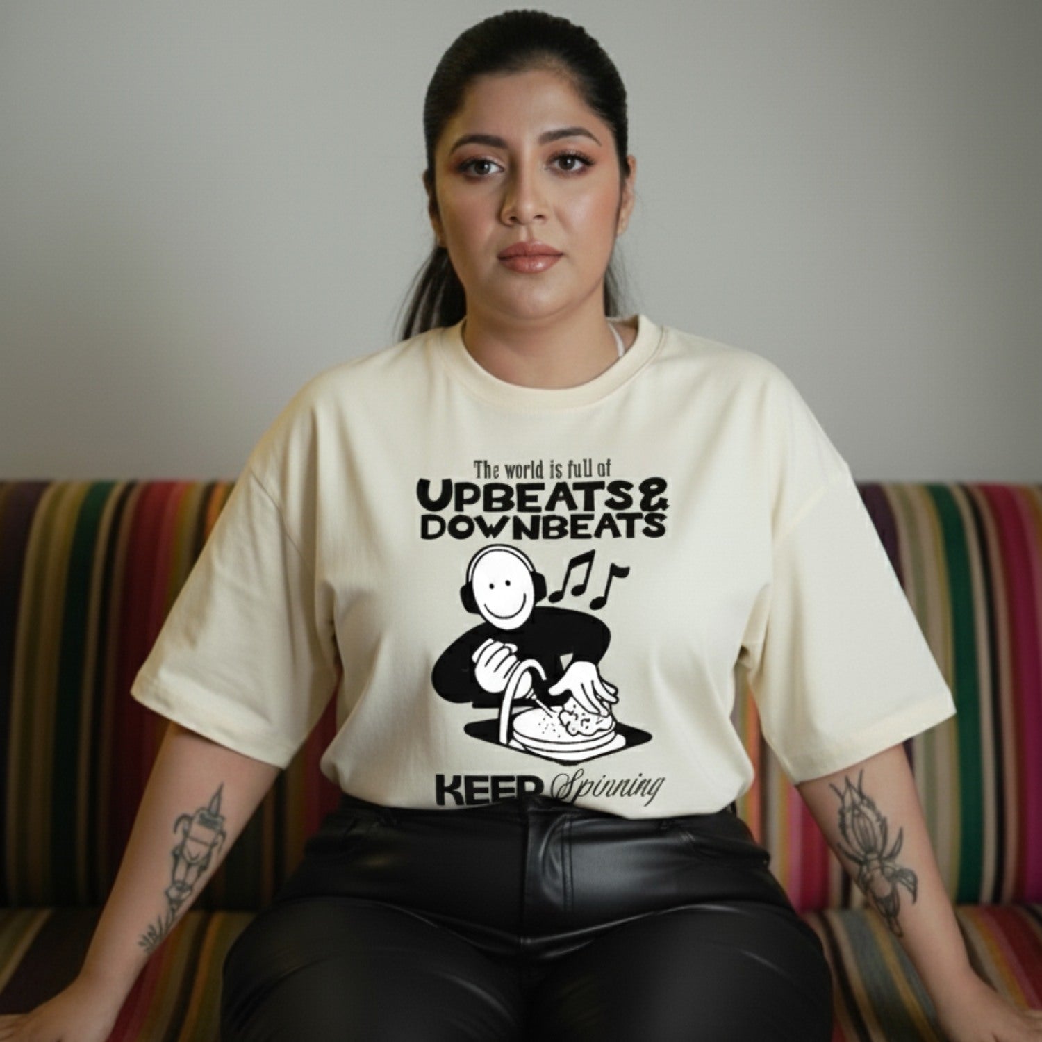 Woman wearing a t-shirt with a graphic design and text, sitting on a colorful couch.