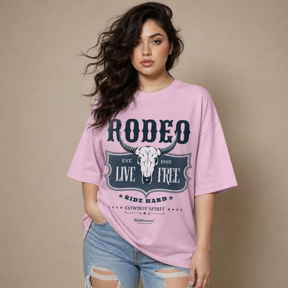 Woman wearing a pink t-shirt with 'Rodeo Live Free' design on a beige background