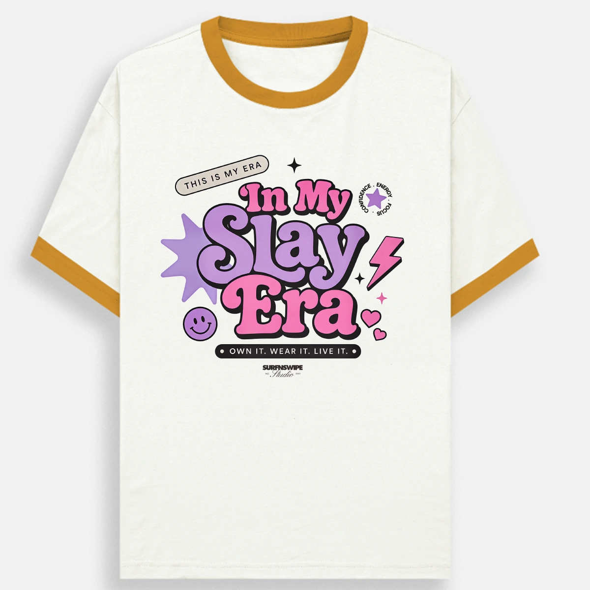 A ringer t-shirt with an off-white body, mustard yellow collar and sleeve trim, featuring a colorful graphic on the chest that reads 'In My Slay Era' in pink and purple bubble letters with a smiley face and lightning bolt details.