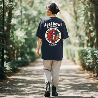 Person wearing a navy blue t-shirt with a colorful graphic and text, walking through a forest.
