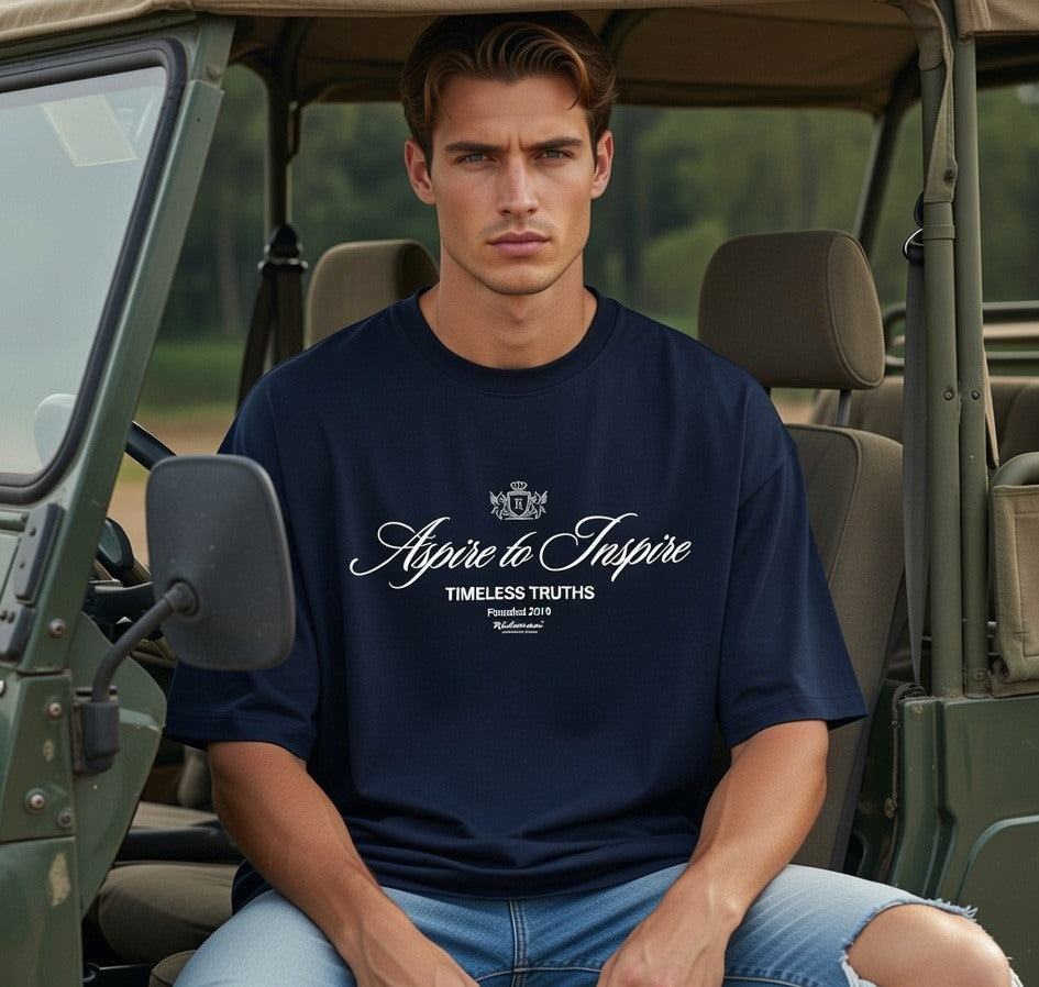 Man wearing a navy blue t-shirt with text sitting inside a vehicle.