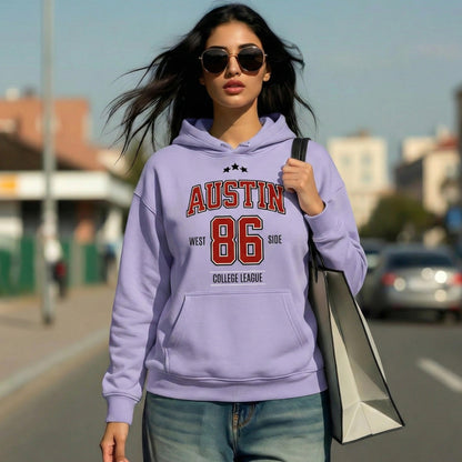 Woman wearing a purple hoodie with 'Austin 86' text, walking outdoors.