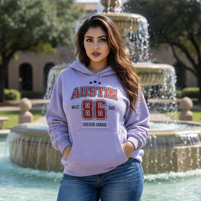 Woman wearing a lavender hoodie with 'Austin West Side College League' text, standing by a fountain.