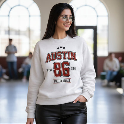 Woman wearing a white sweatshirt with 'Austin 86' text, standing in an outdoor setting.
