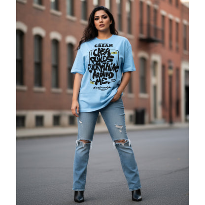 Woman wearing a blue graphic t-shirt and ripped jeans standing in an urban setting.