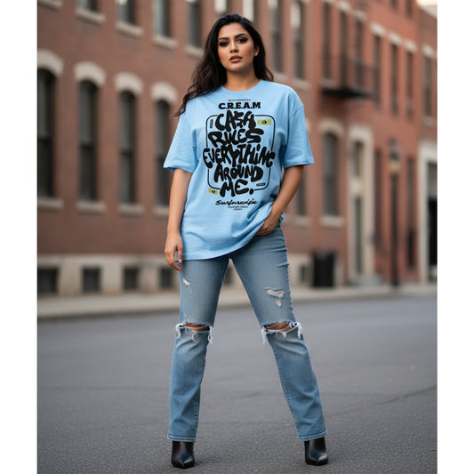 Woman wearing a blue graphic t-shirt and ripped jeans standing in an urban setting.