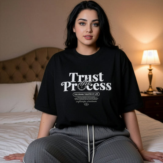 Woman wearing a black t-shirt with 'Trust the Process' text in a bedroom setting