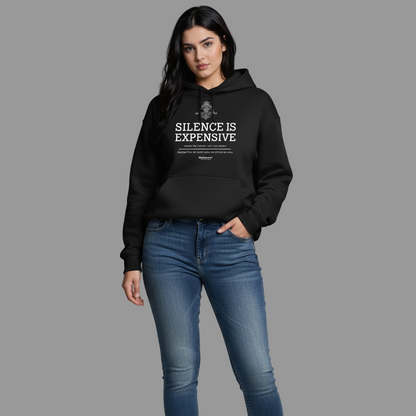 Woman wearing a black hoodie with text and blue jeans on a gray background