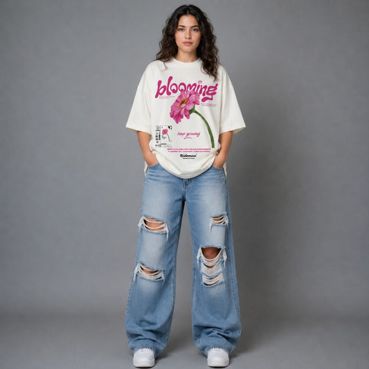 Person wearing a white t-shirt with a graphic design and ripped blue jeans on a gray background