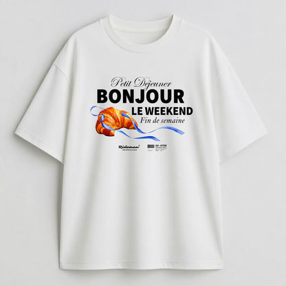 White t-shirt with a graphic design featuring text and a croissant on a light gray background