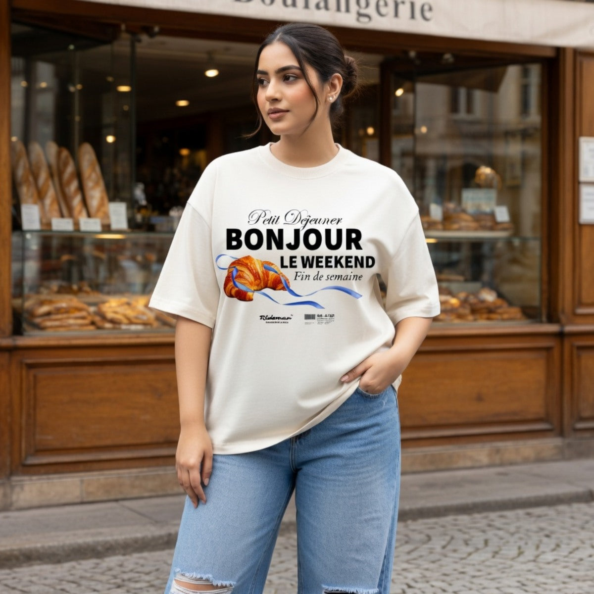 Woman wearing a t-shirt with a graphic design in front of a bakery.
