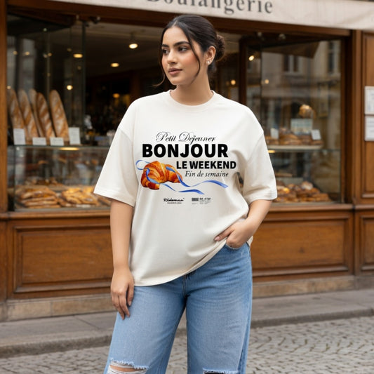 Woman wearing a t-shirt with a graphic design in front of a bakery.