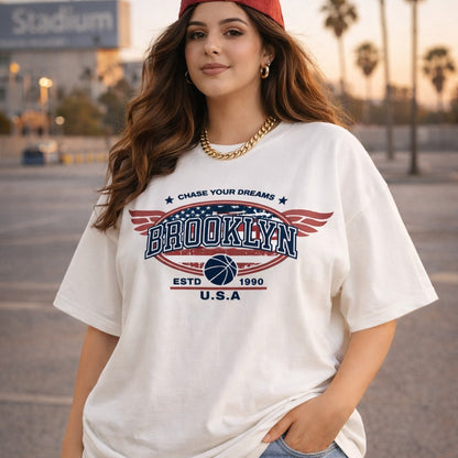 Woman wearing a white t-shirt with 'Brooklyn' design, standing outdoors.