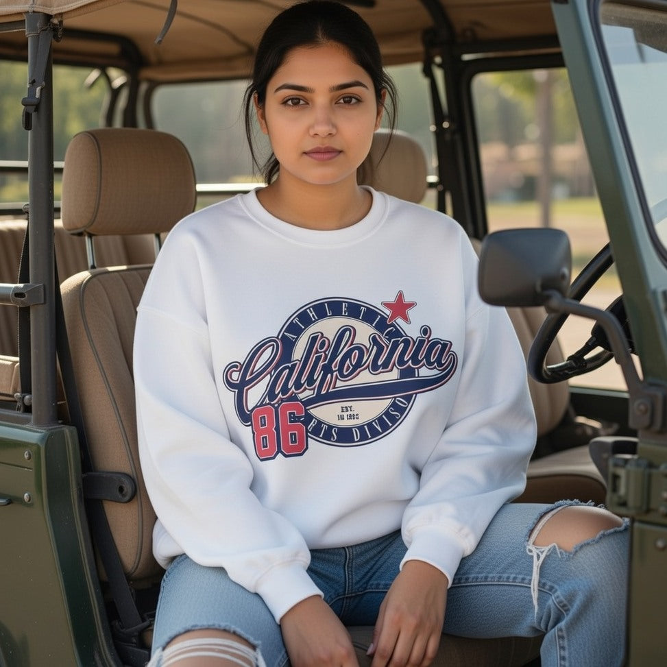 Woman wearing a white sweatshirt with 'California 86' text, sitting inside a vehicle.