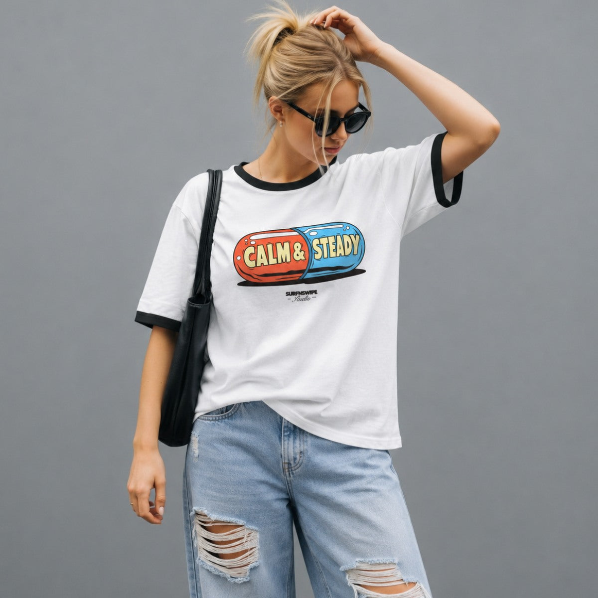 Person wearing a white t-shirt with colorful graphic and text, standing against a gray background