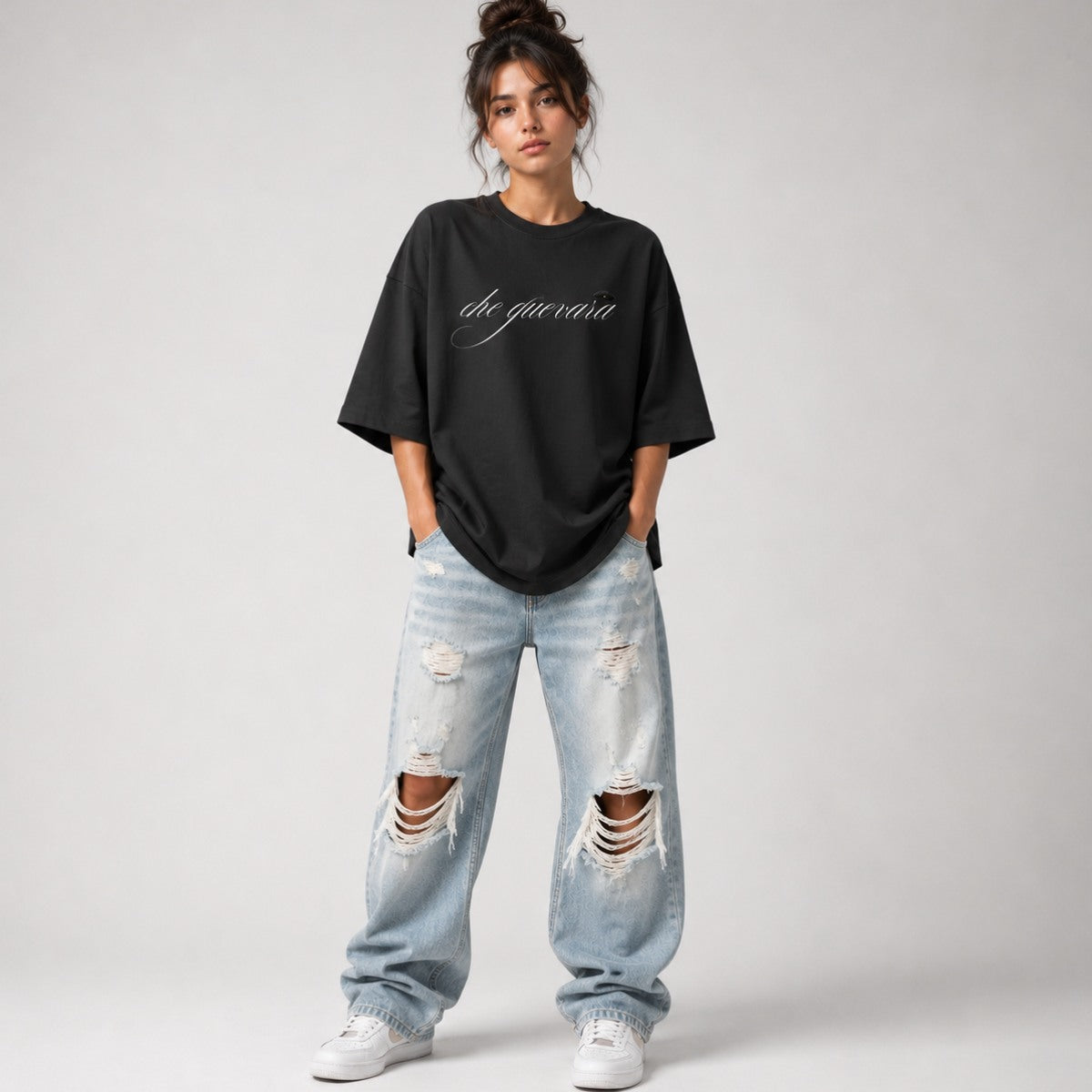 Person wearing a black oversized t-shirt and ripped jeans on a plain background