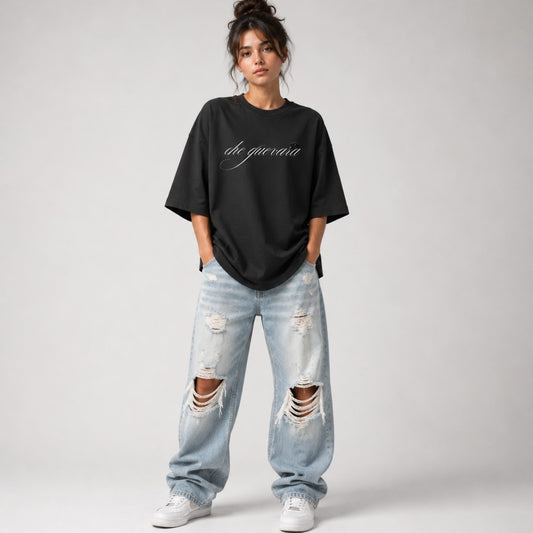 Person wearing a black oversized t-shirt and ripped jeans on a plain background