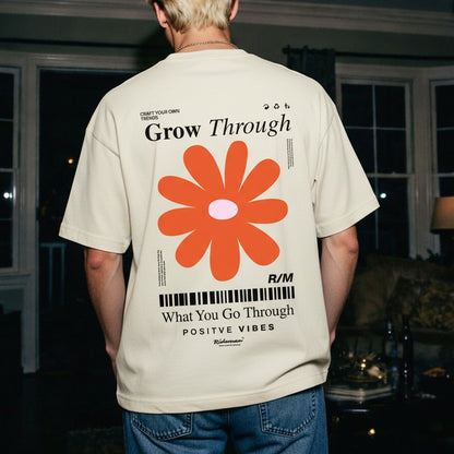 Person wearing a beige t-shirt with a red flower graphic and motivational text on the back.