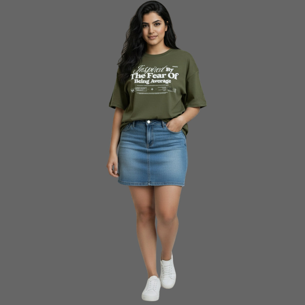 Woman wearing a green t-shirt and blue denim skirt on a plain background