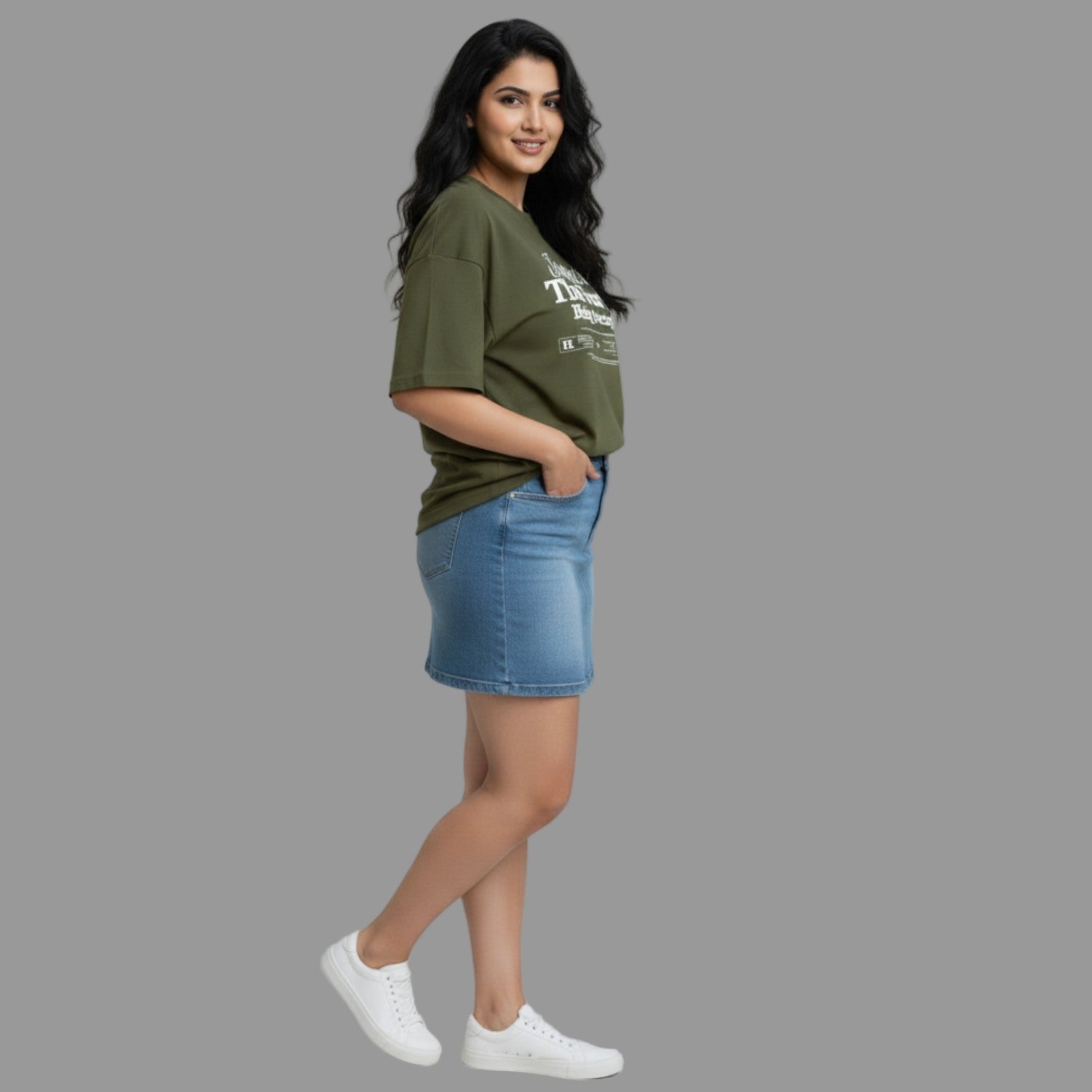 Woman wearing a green t-shirt and blue denim skirt on a gray background