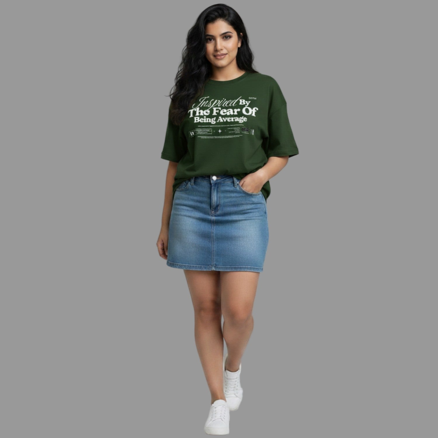 Woman wearing a green t-shirt with text and a denim skirt on a plain background