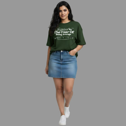 Woman wearing a green t-shirt with text and a denim skirt on a plain background