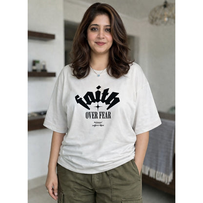 Woman wearing a white t-shirt with 'Faith Over Fear' text in a casual setting.