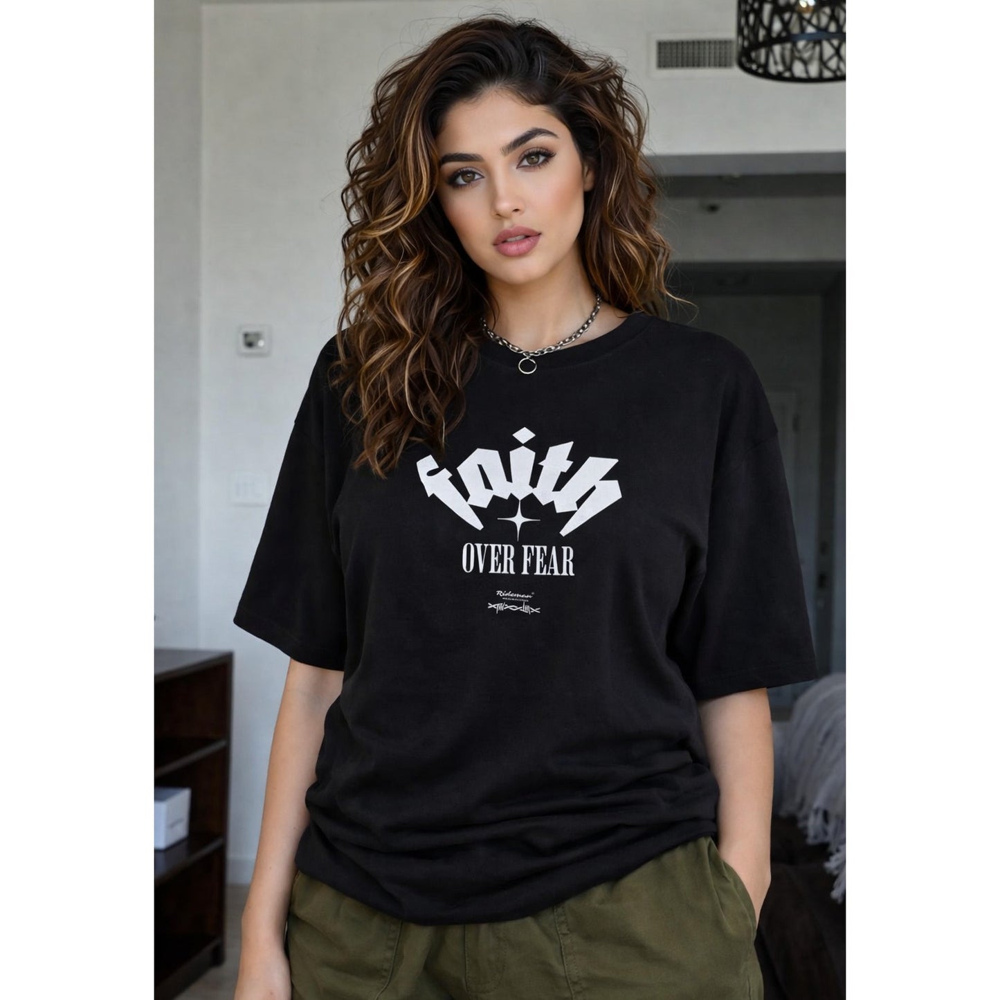 Woman wearing a black t-shirt with 'Faith Over Fear' text in a casual setting.