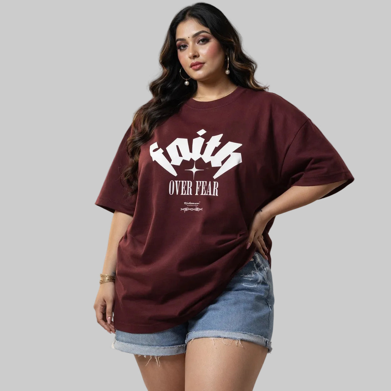 Woman wearing a maroon t-shirt with 'Faith Over Fear' text on a plain background