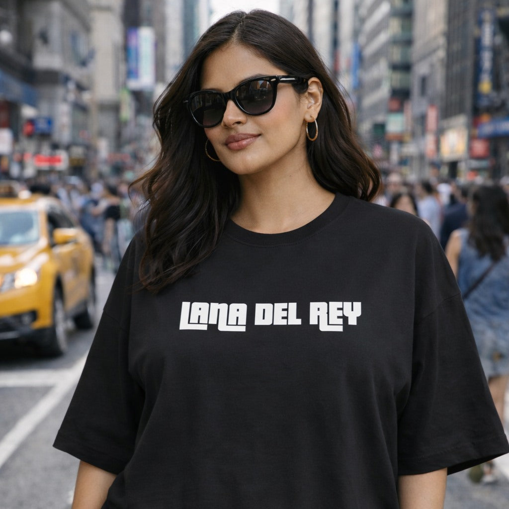 Woman wearing a black t-shirt with 'Lana Del Rey' text on a city street.