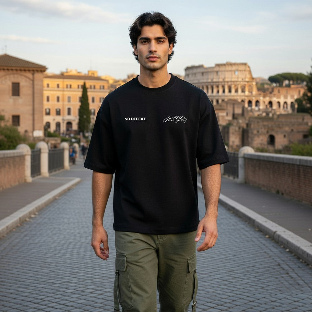 Man wearing a black t-shirt with text standing in front of the Colosseum in Rome.