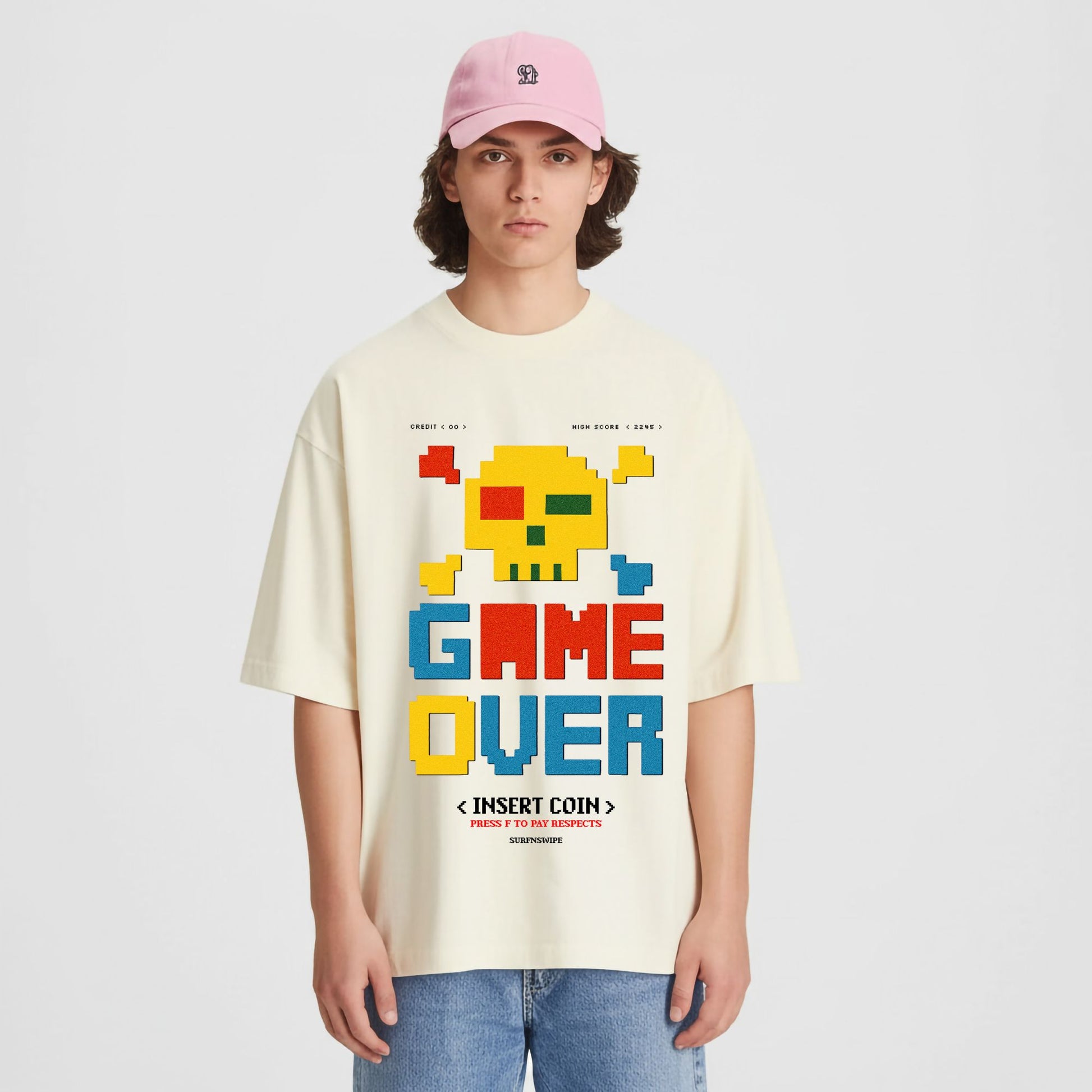 Person wearing a beige t-shirt with a colorful 'GAME OVER' graphic design on a plain background