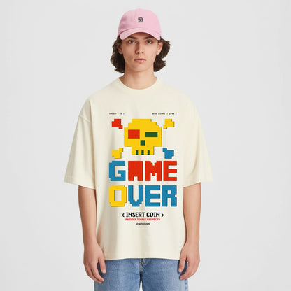 Person wearing a beige t-shirt with a colorful 'GAME OVER' graphic design on a plain background