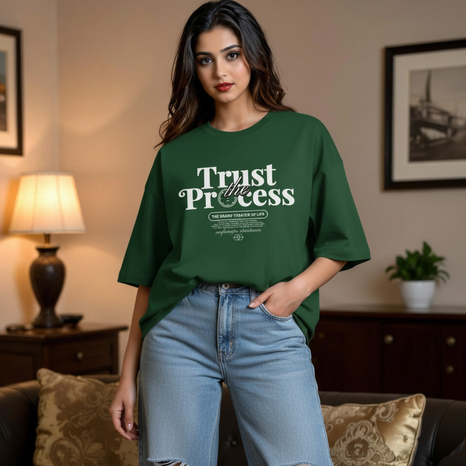 Woman wearing a green t-shirt with 'Trust the Process' text in a living room setting.
