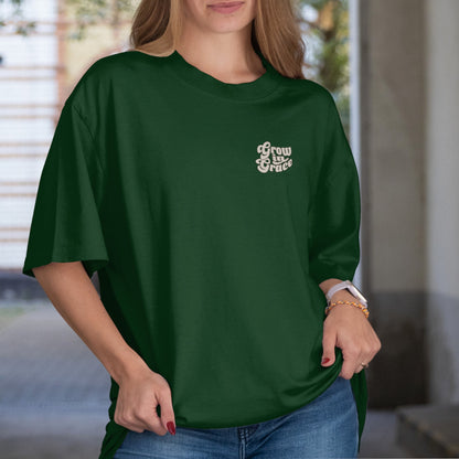 Person wearing a green t-shirt with text Grow in Grace, standing indoors.