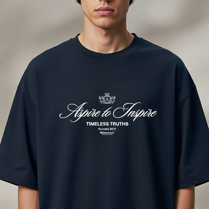 Person wearing a navy blue t-shirt with 'Aspire to Inspire' text and logo on a plain background