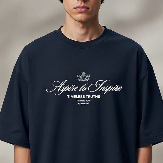 Person wearing a navy blue t-shirt with 'Aspire to Inspire' text and logo on a plain background