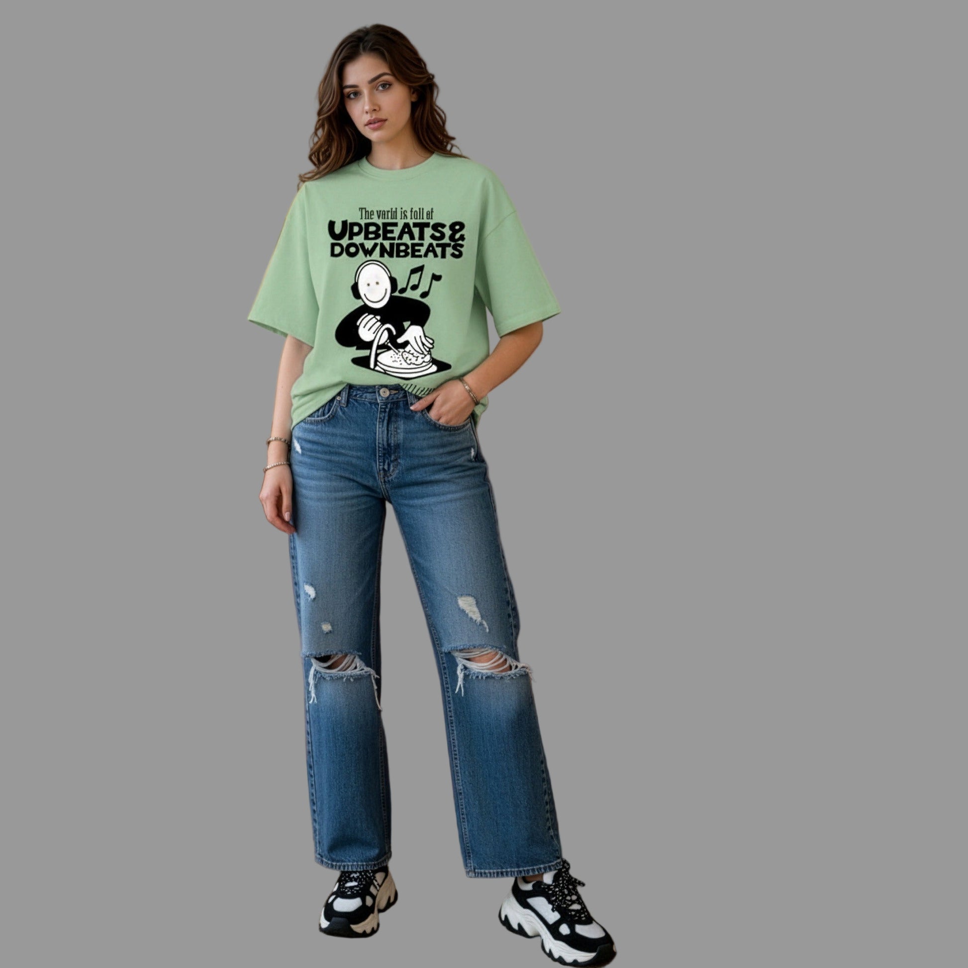 Woman wearing a green t-shirt with text and graphics, standing in a living room.