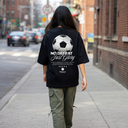 Person wearing a black t-shirt with a soccer ball design and text on the back, walking on a city street.