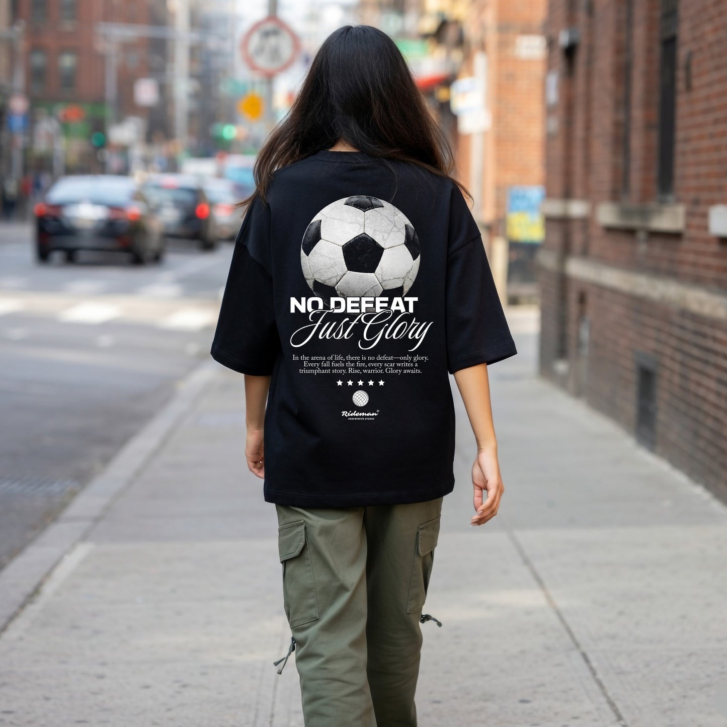 Person wearing a black t-shirt with a soccer ball design and text on a city street.