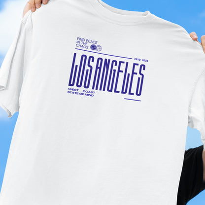 White t-shirt with 'Los Angeles' text held against a blue sky