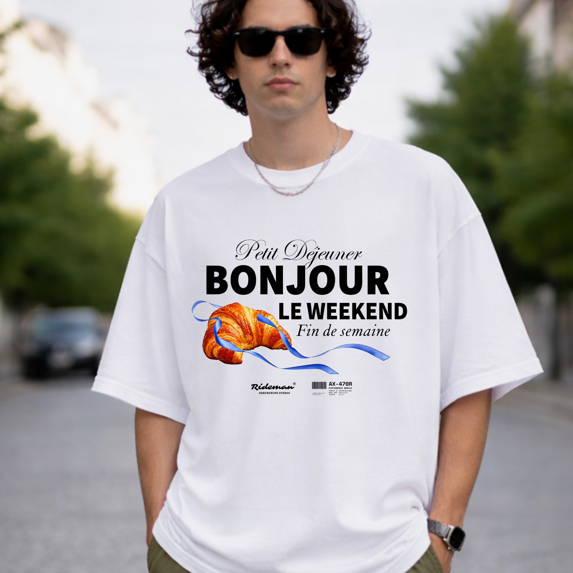 Person wearing a white t-shirt with a graphic design and text outdoors.