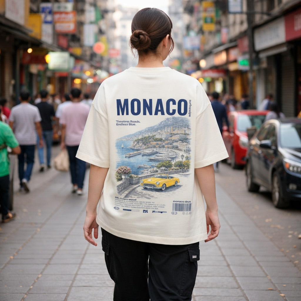 Person wearing a white t-shirt with 'MONACO' design on a city street.