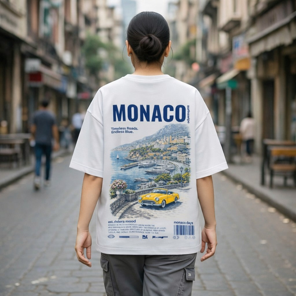 Person wearing a white t-shirt with a Monaco-themed design on a city street.