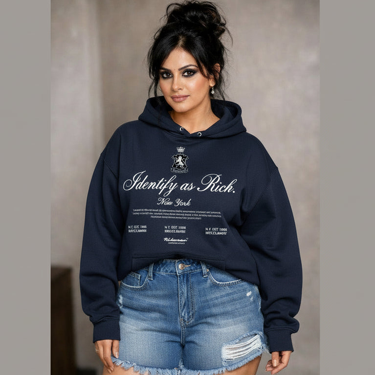 Woman wearing a navy hoodie with text and denim shorts against a neutral background