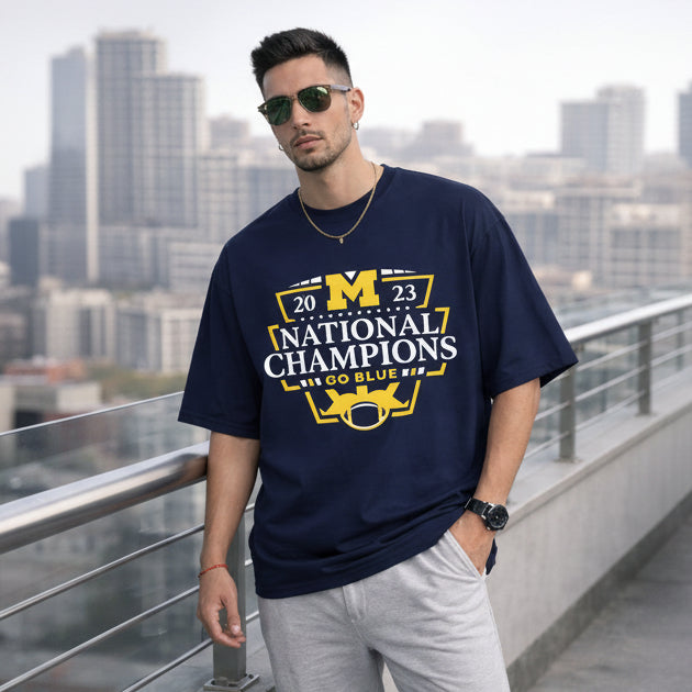 Man wearing a navy blue t-shirt with '2023 National Champions' text and graphics, standing on a rooftop with cityscape background.