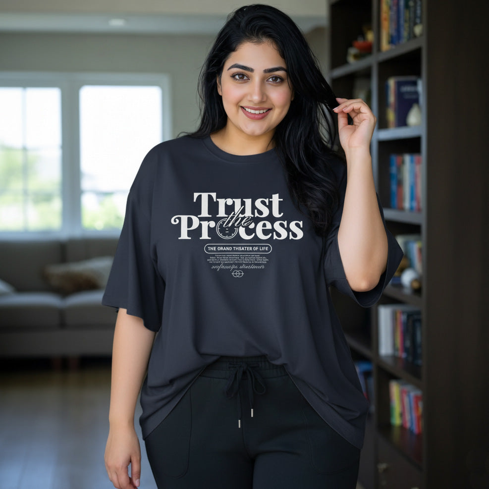 Woman wearing a black t-shirt with 'Trust the Process' text in a living room.